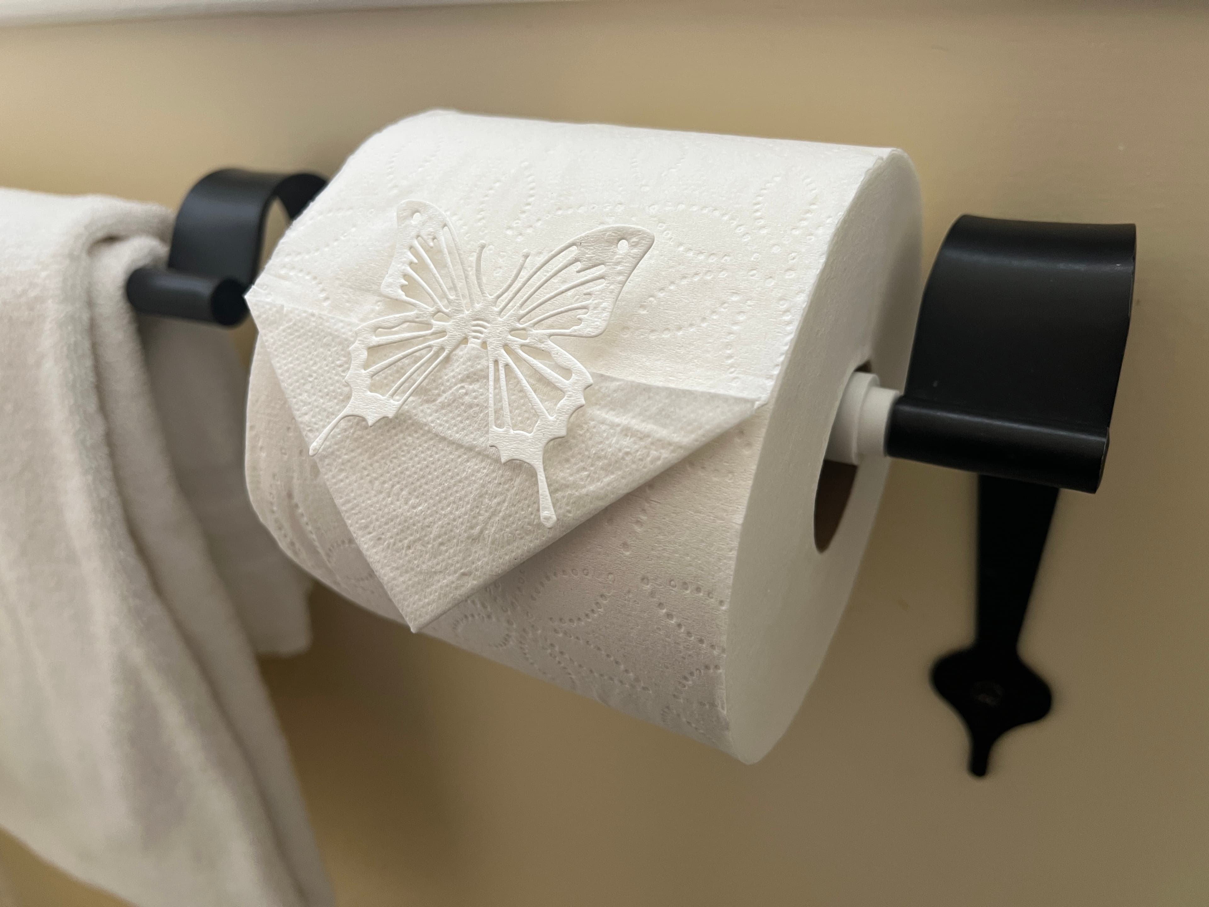 A roll of decorative paper towels with a butterfly design sits on a black holder.
