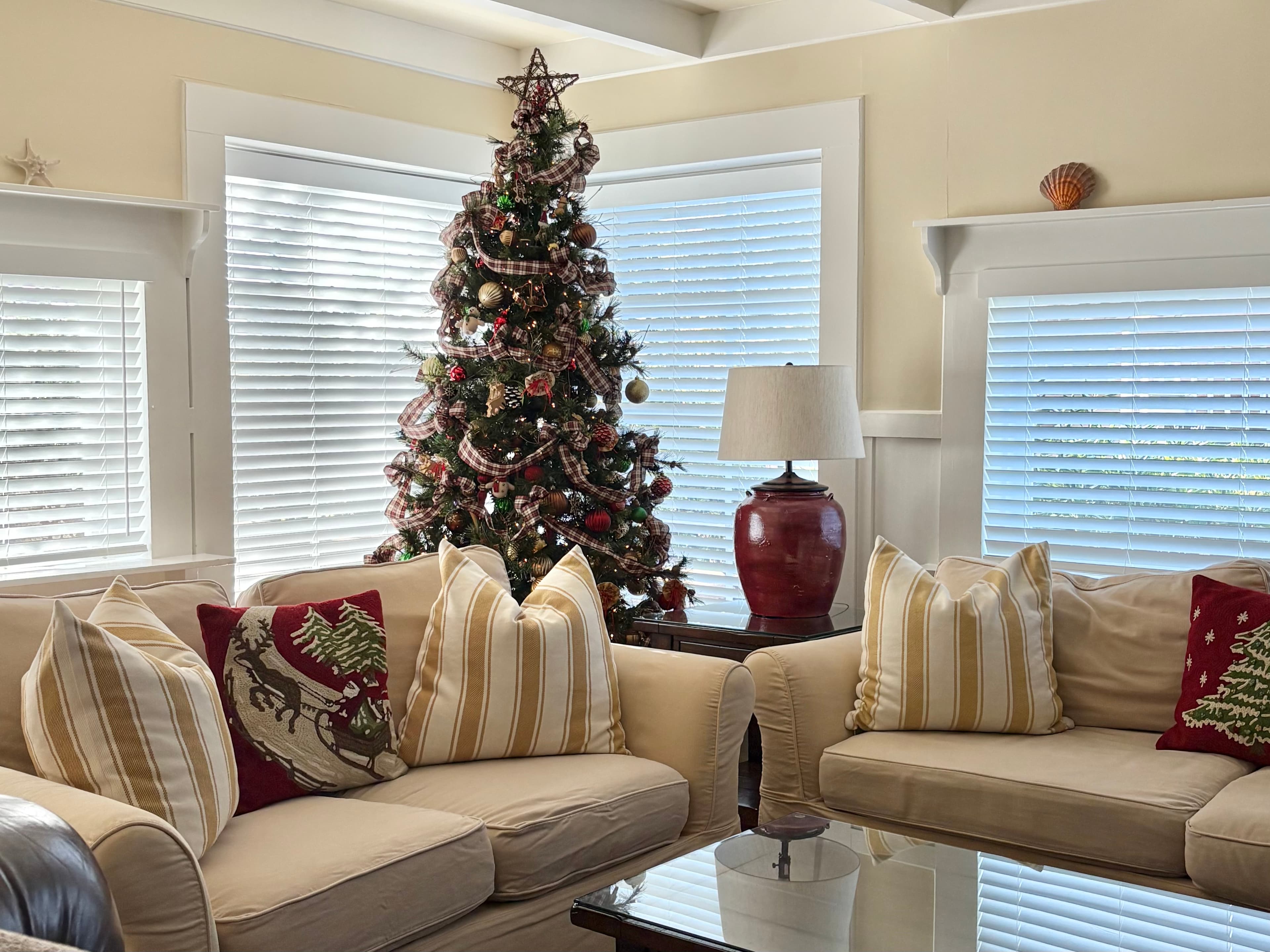 A cozy living room decorated for the holidays with a Christmas tree and soft furnishings.
