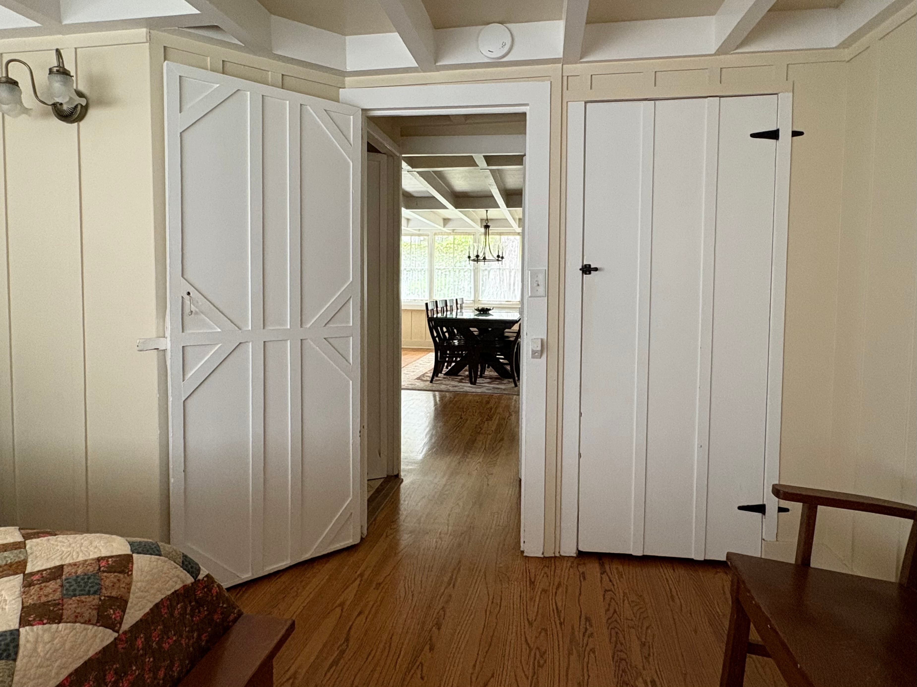 Interior view showing an open doorway leading to a dining area with a table and chairs, flanked by two white doors.