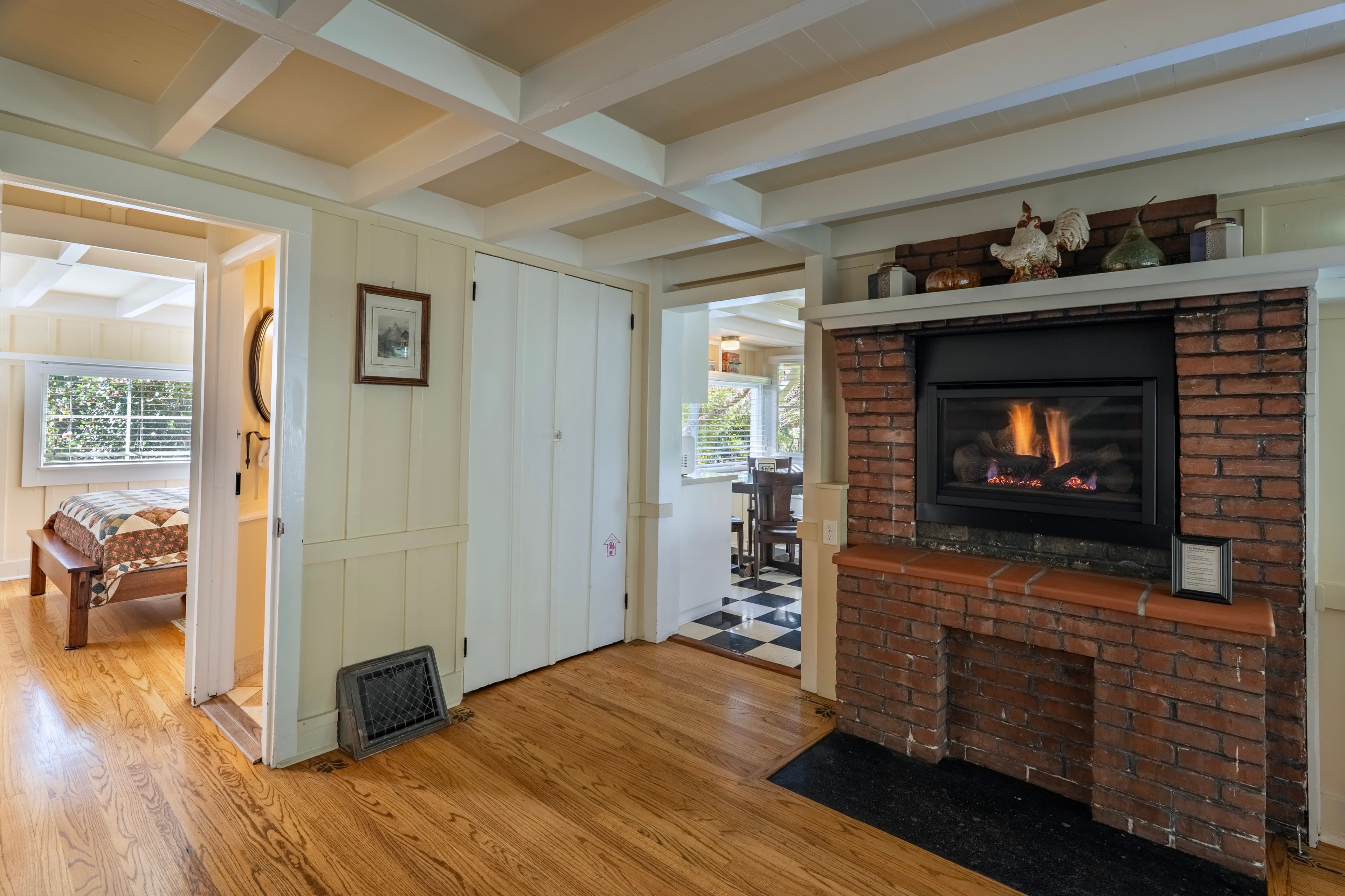 Cozy living space featuring a brick fireplace, wooden floors, and connected rooms.