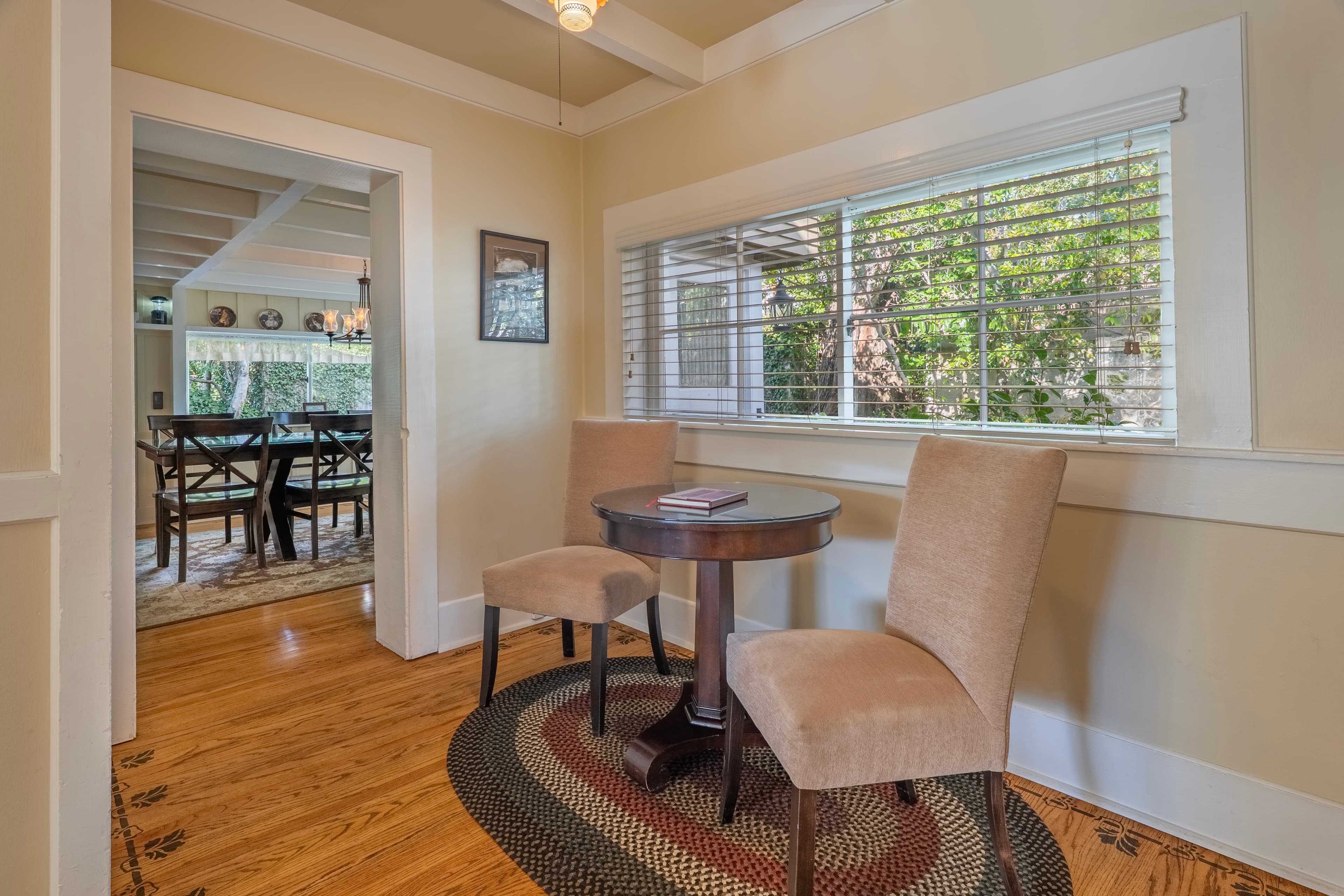 A cozy nook with two chairs and a small table, featuring a window that overlooks greenery.