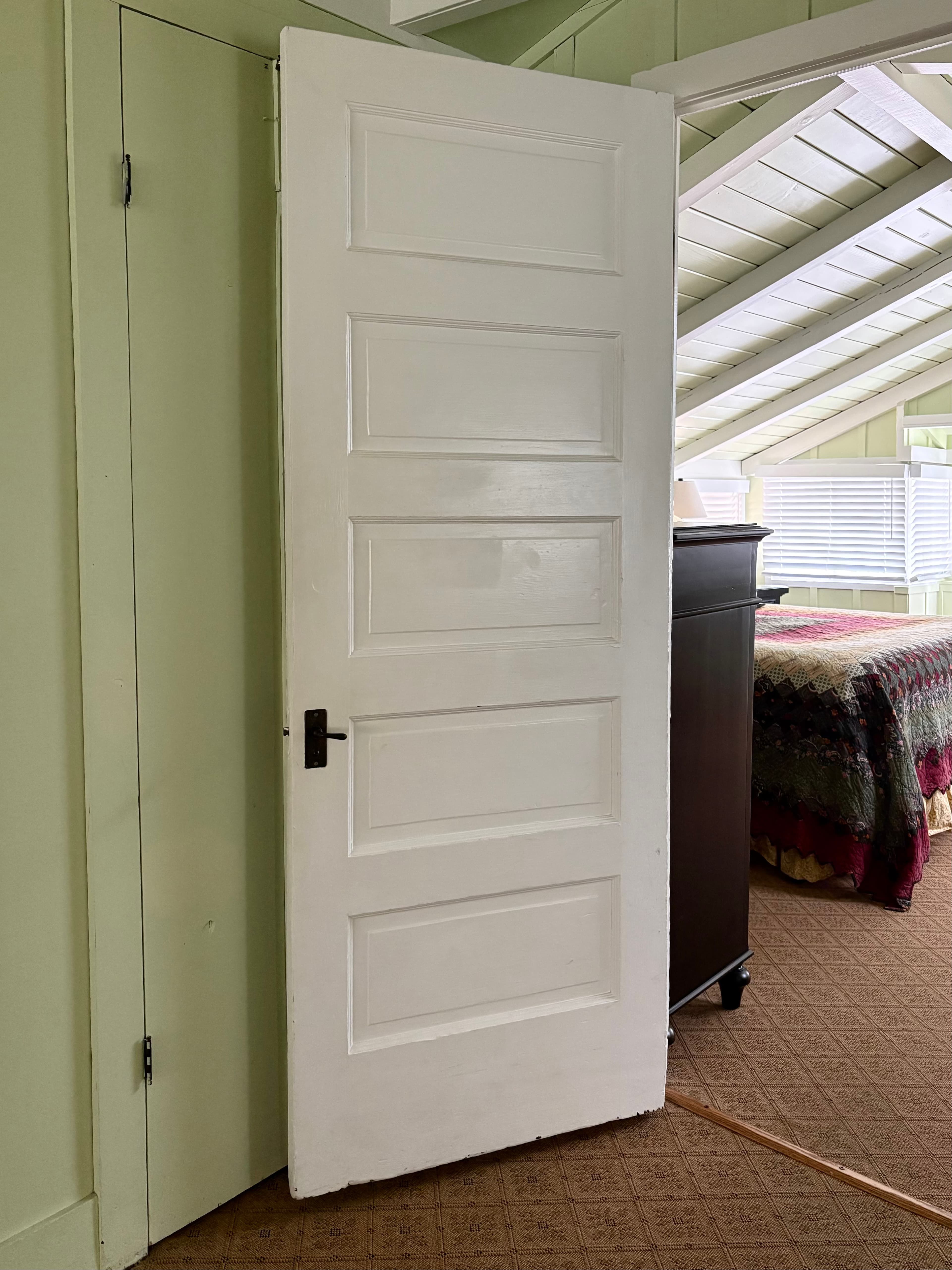 Old door open with a glimpse of a bedroom inside.